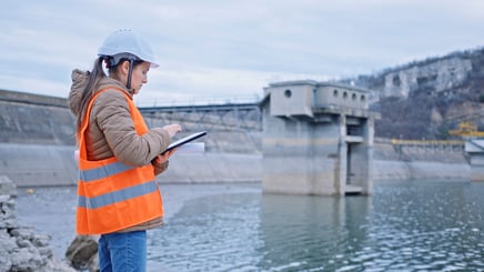 Female engineer working on a tablet at a hydroelectric dam.