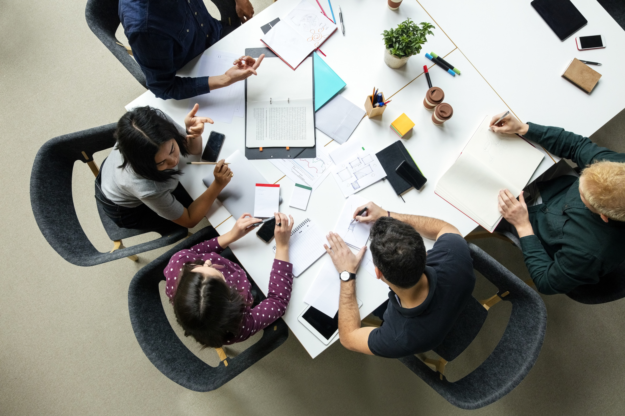 An overhead view of people gathered around a table working on documents.