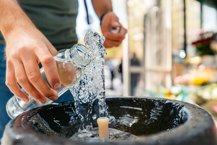 A person fills a resuable water at a public drinking fountain.