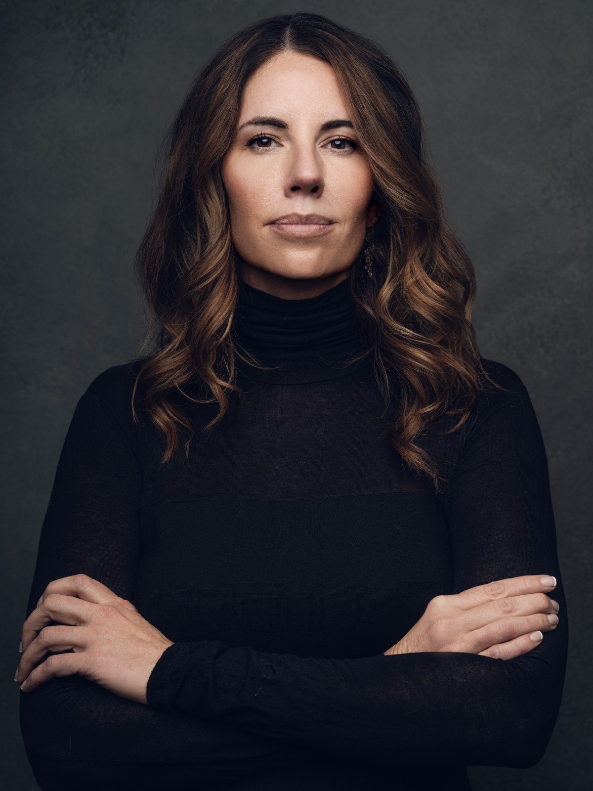 Sara Larsen in a black turtleneck with her arms crossed.