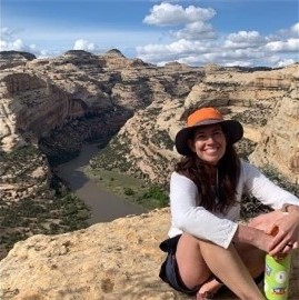 Sara Larsen sitting on a rock edge of a canyon.